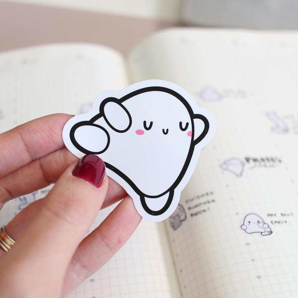 Hand holding a cute cloud-shaped sticker with a smiley face on a notebook background