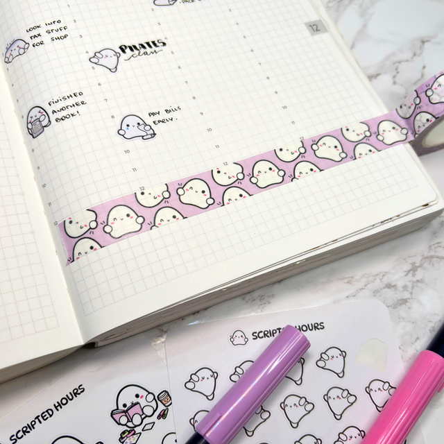 A white gridded planner on a marble surface, featuring a strip of purple washi tape with smiling white ghost patterns, alongside hand-drawn ghost characters illustrating daily tasks like Pilates class and finished another book, with Scripted Hours ghost sticker sheets and pink and purple markers nearby