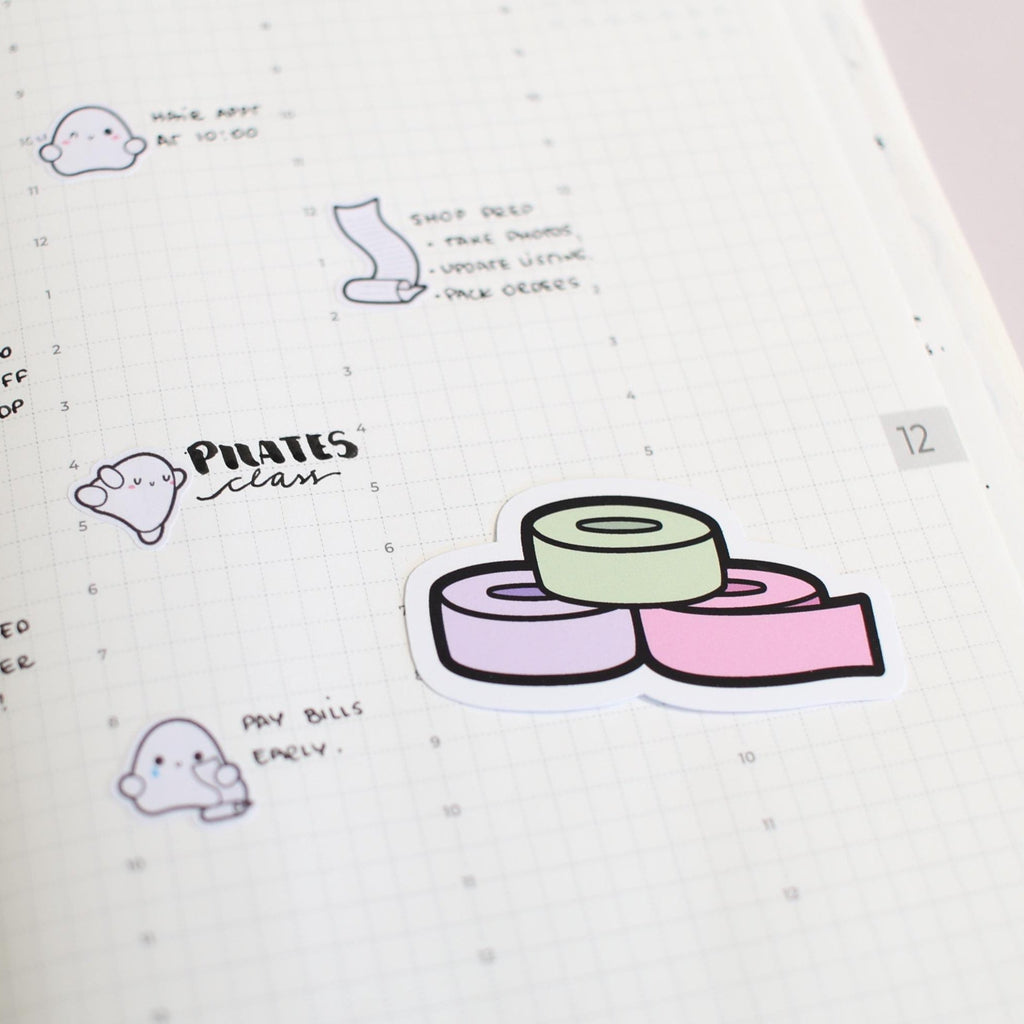 Illustrated washi tape rolls with text on a notebook page