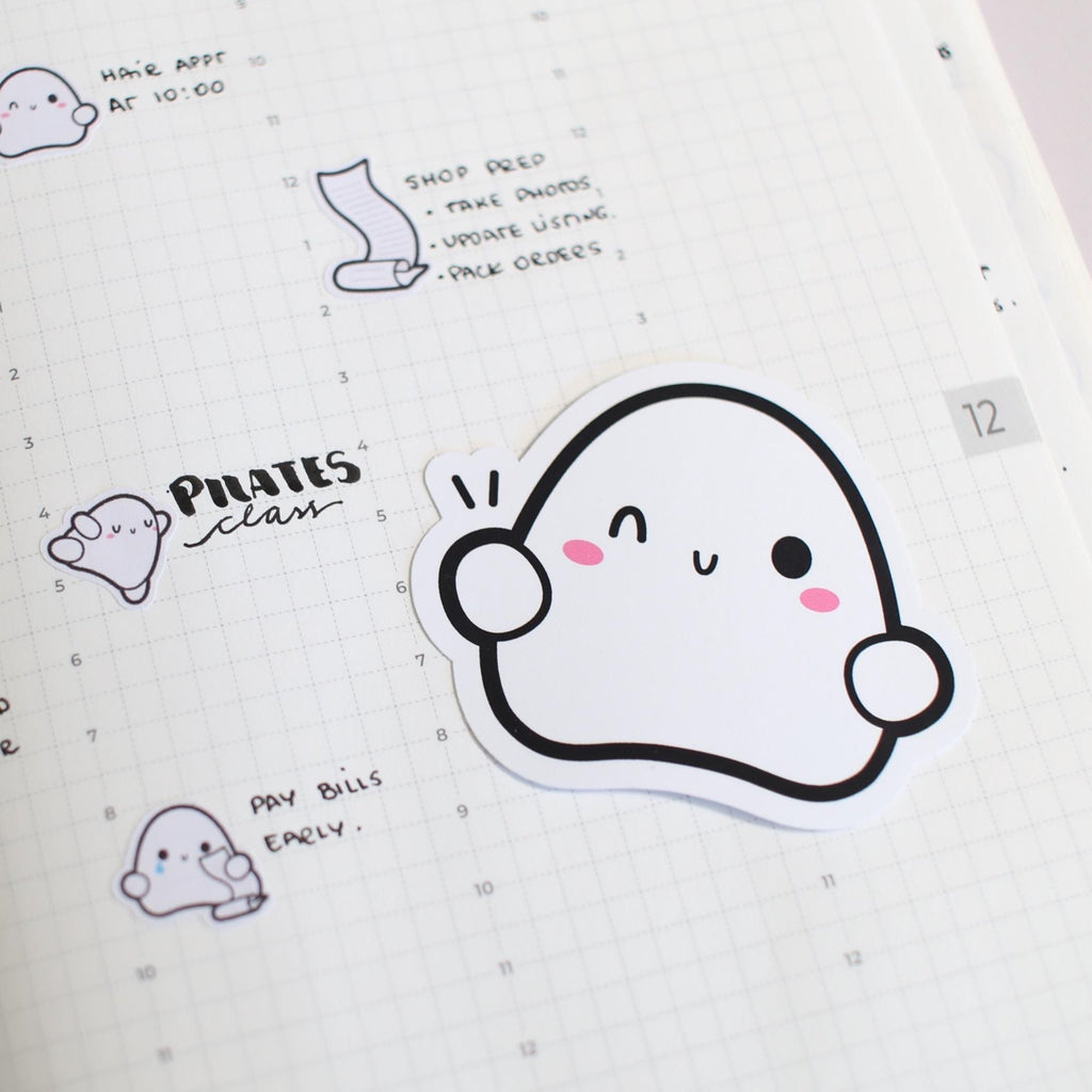 Sticker with a cute ghost design on a notebook page with text and other stickers.