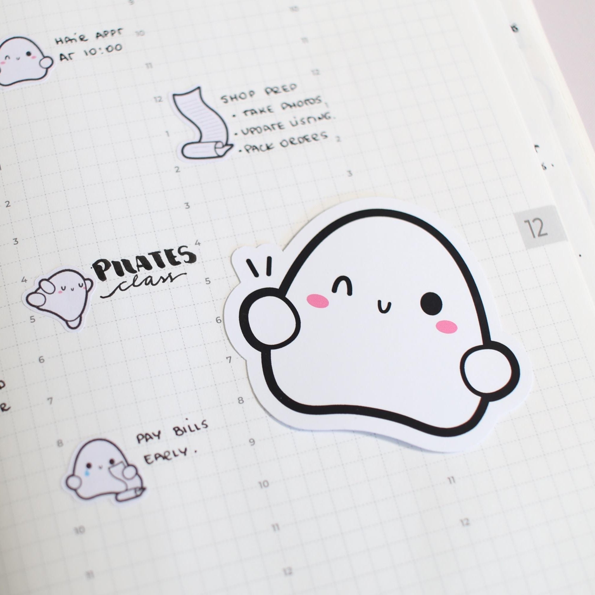 Sticker with a cute ghost design on a notebook page with text and other stickers.